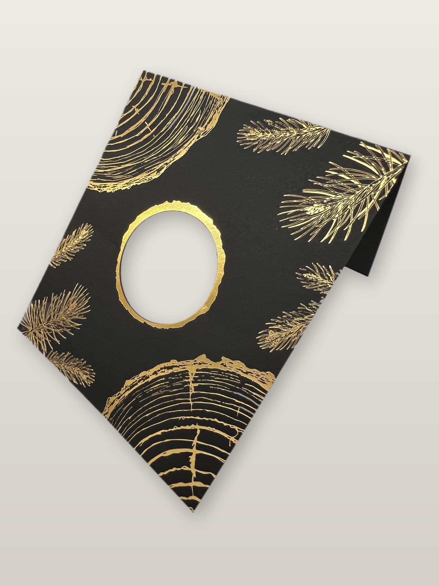 Gold foil stamped rings and pine needles on black card stock